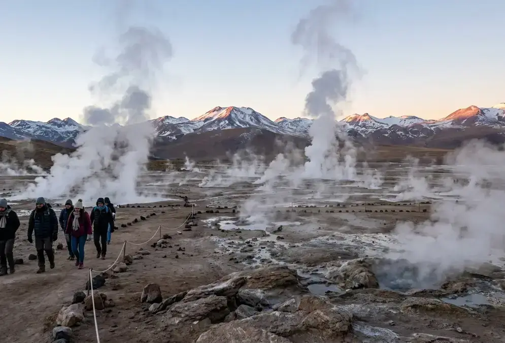 Atacama Desert plateau at dawn with steam rising from El Tatio geyser fields at 4,300 m elevation, pale volcanic sky above thin Andean air, the high-altitude terrain where Atacama altitude sickness risk peaks for visitors