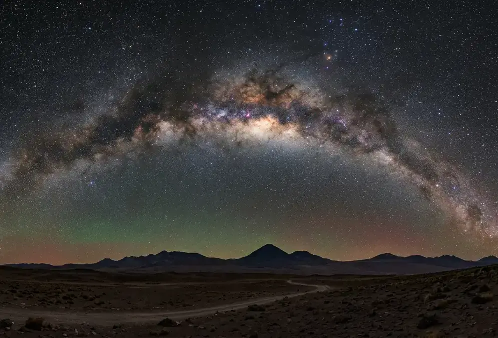 Milky Way galactic core arching overhead above the Atacama Desert at new moon, silhouette of volcanic peaks on the horizon, Bortle 1 dark sky over San Pedro de Atacama