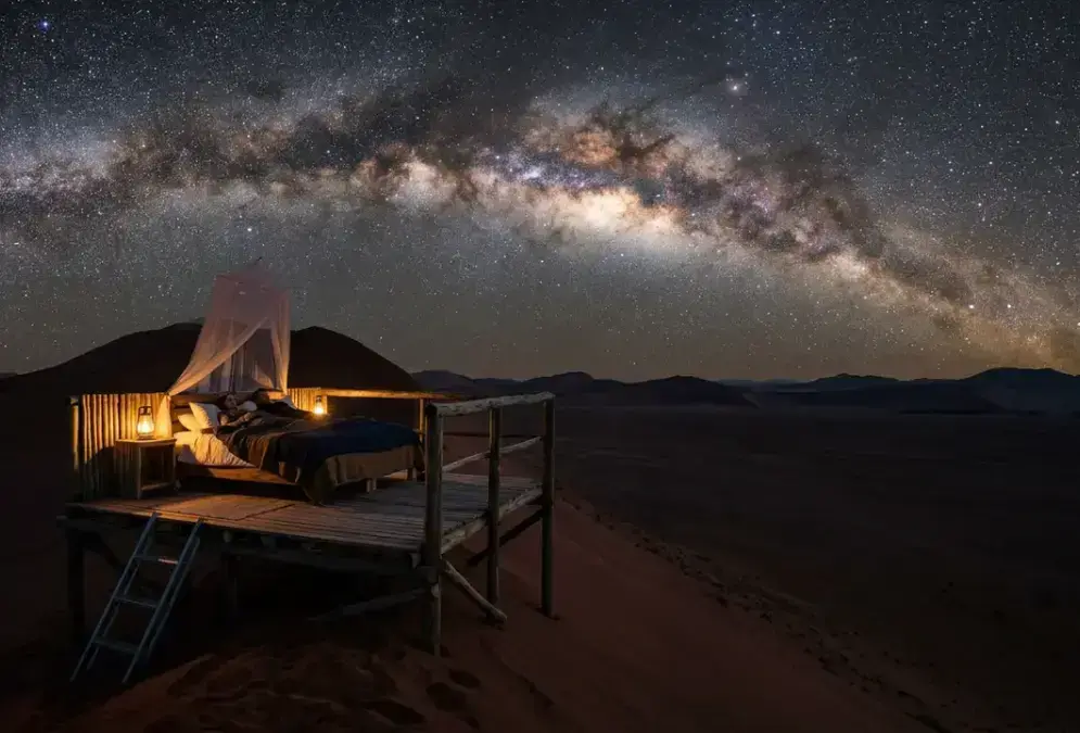 Star Bed sleep-out platform atop a 250-metre dune in NamibRand Nature Reserve at night, Milky Way arching over the Namib Desert, one of the best stargazing spots in NamibRand