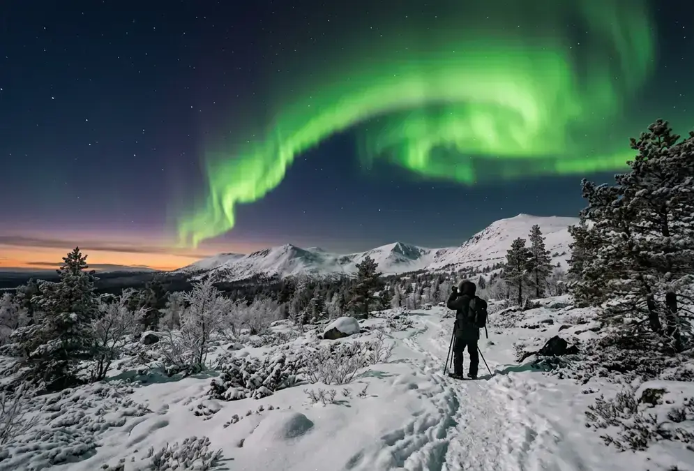 Green aurora curtain over a snow-covered fell in Finnish Lapland at dusk in late September, illustrating the best time to see northern lights in Lapland during the equinox season