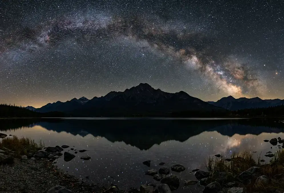 Star-filled night sky above Pyramid Lake in Jasper National Park during the September-October shoulder season, Milky Way arching over dark mountain silhouettes, the best time to stargaze in Jasper