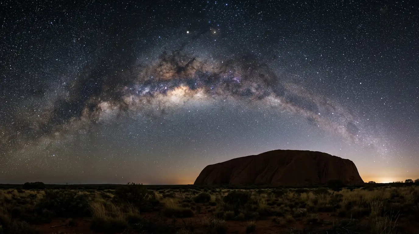 Milky Way arching over Uluru's dark silhouette at night in Australia's Red Centre, best time to see stars at Uluru