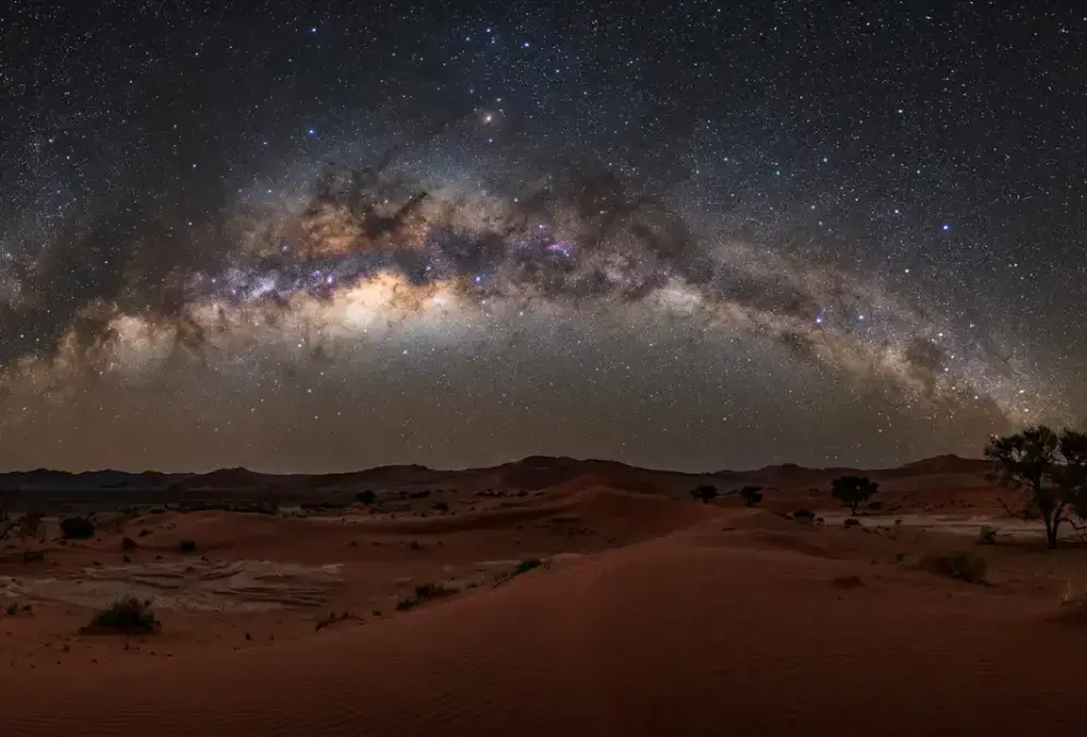 Milky Way and Southern Cross arcing over red dunes in NamibRand Nature Reserve at night, illustrating why NamibRand is worth it for stargazing in Africa's Gold Tier Dark Sky Reserve