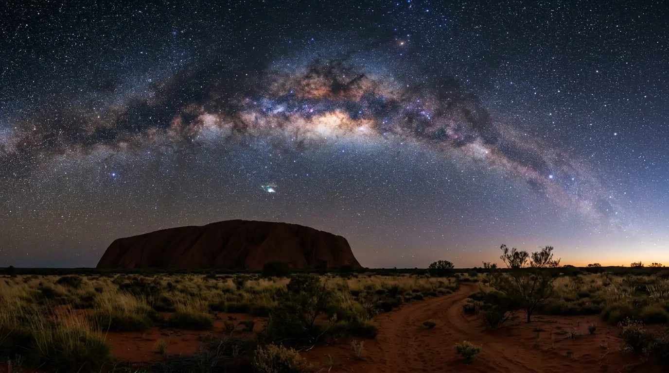 Milky Way galactic core rising over Uluru's silhouette in Australia's Red Centre, illustrating why Uluru is worth it for stargazing under a dark Southern Hemisphere sky