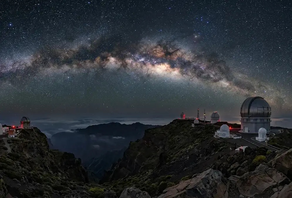 Milky Way arching above the Roque de los Muchachos Observatory domes at night on La Palma, illustrating this La Palma stargazing FAQ with Bortle 1-2 dark skies over the Caldera de Taburiente rim