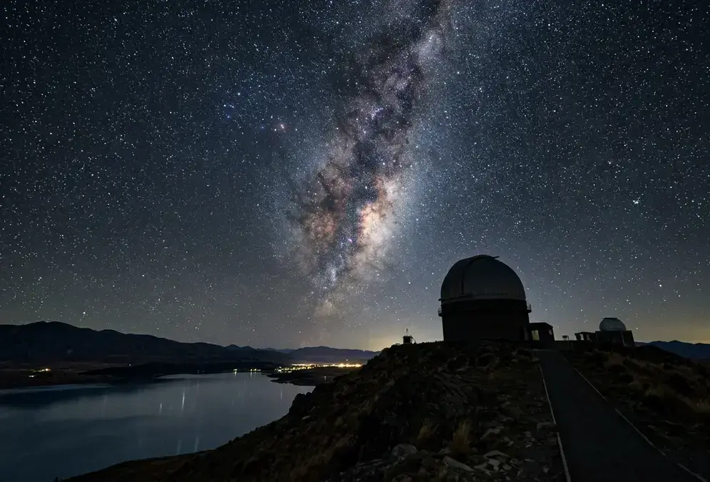 Mt John Observatory guide: the dome's silhouette against a star-thick Milky Way sky above Lake Tekapo, New Zealand's largest research observatory at the Aoraki Mackenzie Gold Tier dark sky reserve