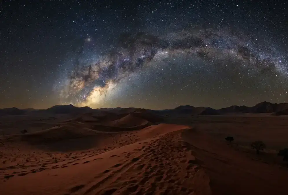 Wide-angle night photo of the Milky Way over red dunes in NamibRand Nature Reserve, illustrating Namib Desert dark sky conservation in Africa's only Gold Tier International Dark Sky Reserve