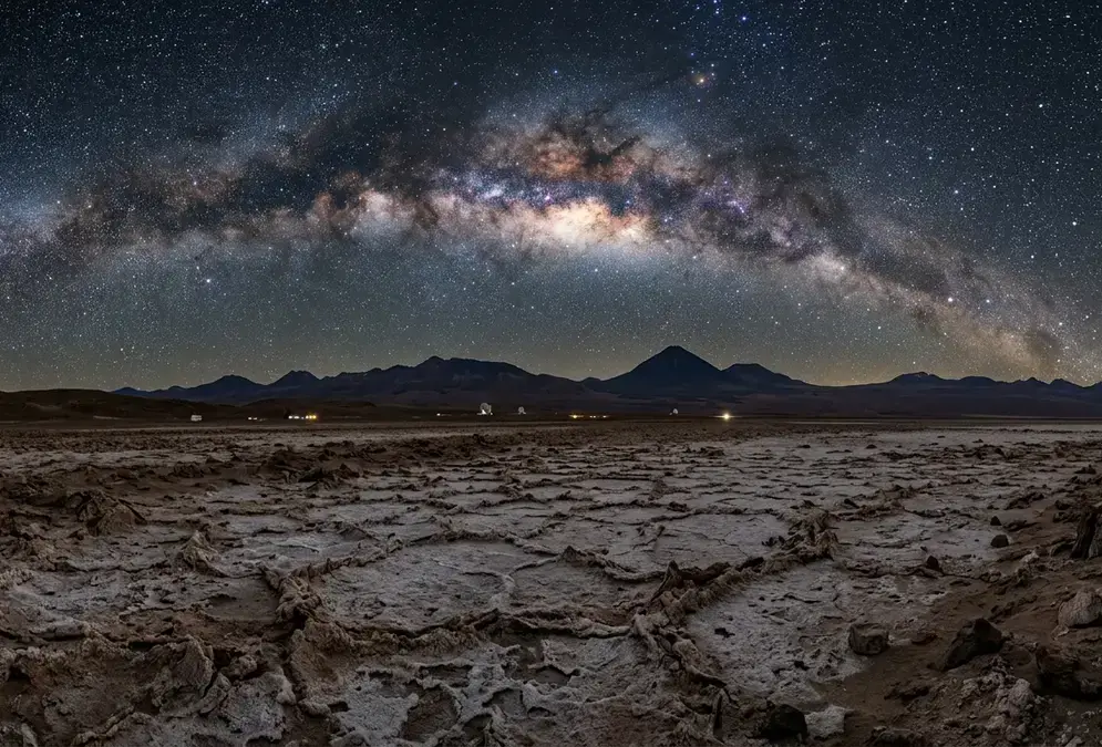 The Atacama Desert at night showing the driest terrain on Earth, parched salt flats and volcanic peaks under a sky blazing with stars, the Milky Way galactic core visible overhead at the world's driest non-polar desert